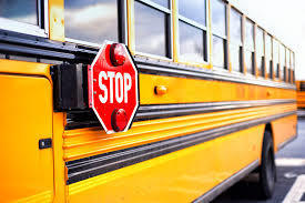 side of yellow school bus with red stop sign attatched to bus