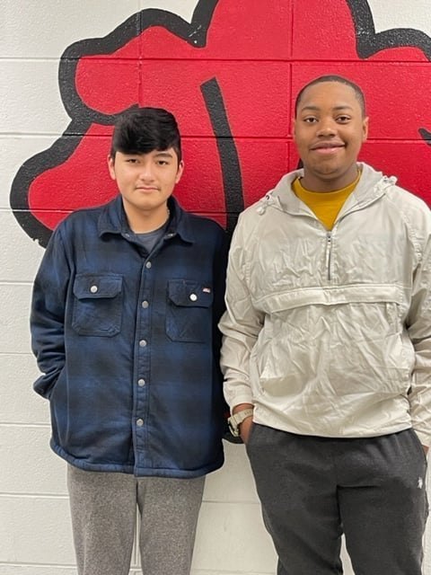 two rotary club students in front of white brick wall with redbug painted on the wall
